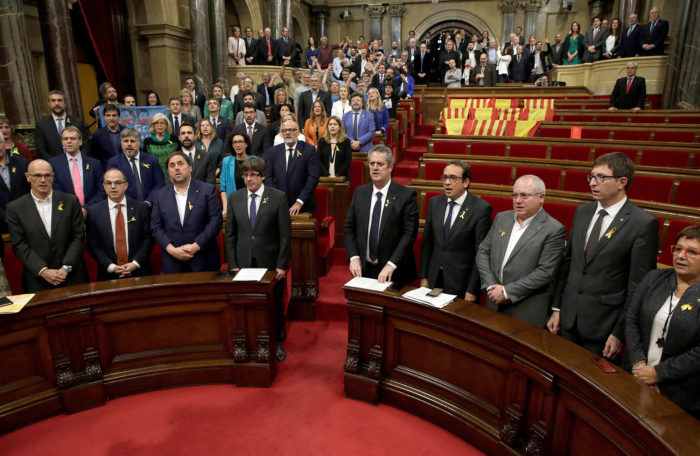 Barcelona, 2017. október 27. Carles Puigdemont katalán elnök (b4) és Oriol Junqueras alelnök (b3) éneklik a nemzeti himnuszt a katalán parlament üléstermében Barcelonában 2017. október 27-én, miután a katalán parlament függetlenségi pártjai megszavazták a független Katalán Köztársaság létrehozását célzó javaslatot. Az ellenzéki Ciudadanos (Állampolgárok) nevű liberális középutas párt, a Katalán Szocialista Párt (PSC) és a Spanyolországban kormányzó konzervatív Néppárt (PP) képviselői a szavazás előtt elhagyták az üléstermet, utóbbiak előtte padjaikat spanyol és katalán zászlókkal terítették le.(MTI/EPA/Alberto Estevez)