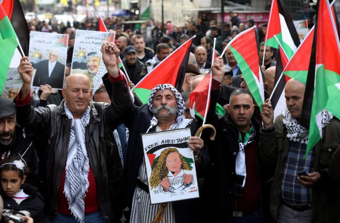 Náblusz, 2017. december 31. Palesztin tüntetők a ciszjordániai Nábluszban 2017. december 31-én. A tüntetők Donald Trump amerikai elnök döntése miatt tiltakoztak, amely szerint az Egyesült Államok Tel-Aviv helyett Jeruzsálemet tekinti Izrael fővárosának. A plakát Ahed Tamimi palesztin aktivista szabadon bocsátását követeli. (MTI/EPA/Abed al-Haslamun)