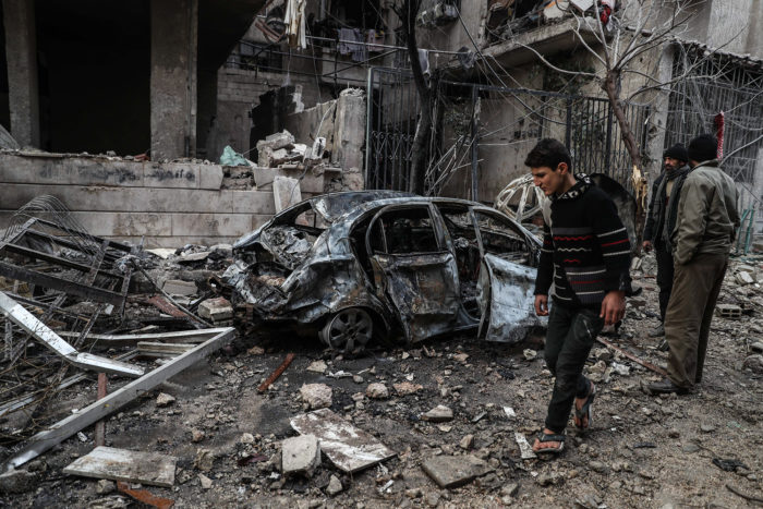 Hamúria, 2018. január 7. Megsemmisült épületek romjai közt mennek emberek a felkelők kezén lévő szíriai Hamúria városában 2018. január 6-án. Legkevesebb 17 civil vesztette életét a szíriai fővároshoz közeli, ostromlott kelet-gútai térségben az orosz légierő legutóbbi csapásai következtében. (MTI/EPA/Mohammed Badra)