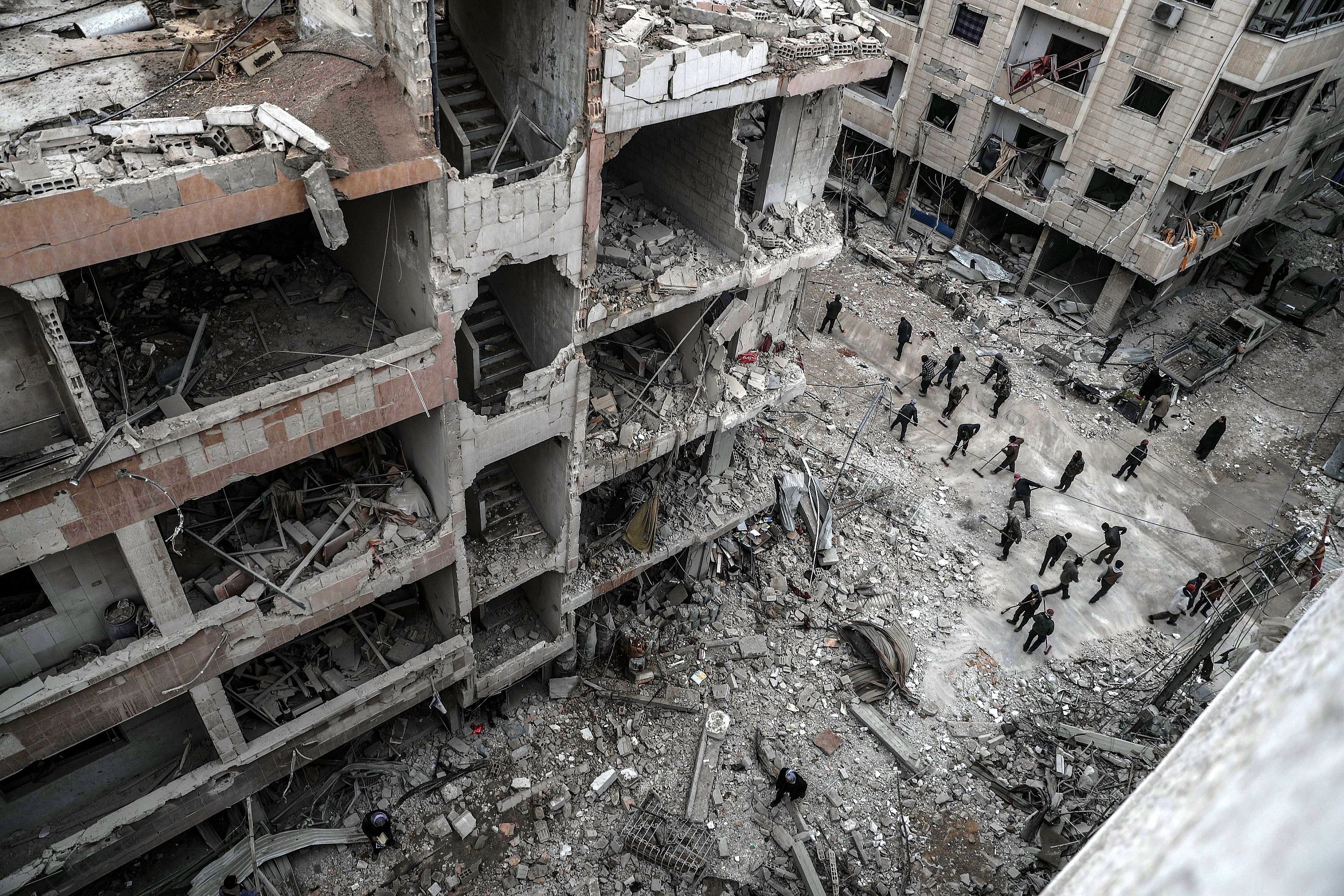 Dúma, 2018. február 22. Szíriai civilek épülettörmeléket takarítanak egy útról a felkelők uralta kelet-gútai Dúma városban 2018. február 22-én, a szíriai kormánnyal szövetséges erők újabb légicsapásai után. A kelet-gútai térséget ezen a napon ért légi- és tüzérségi támadások halálos áldozatainak száma 46-ra emelkedett. (MTI/EPA/Mohamed Badra)