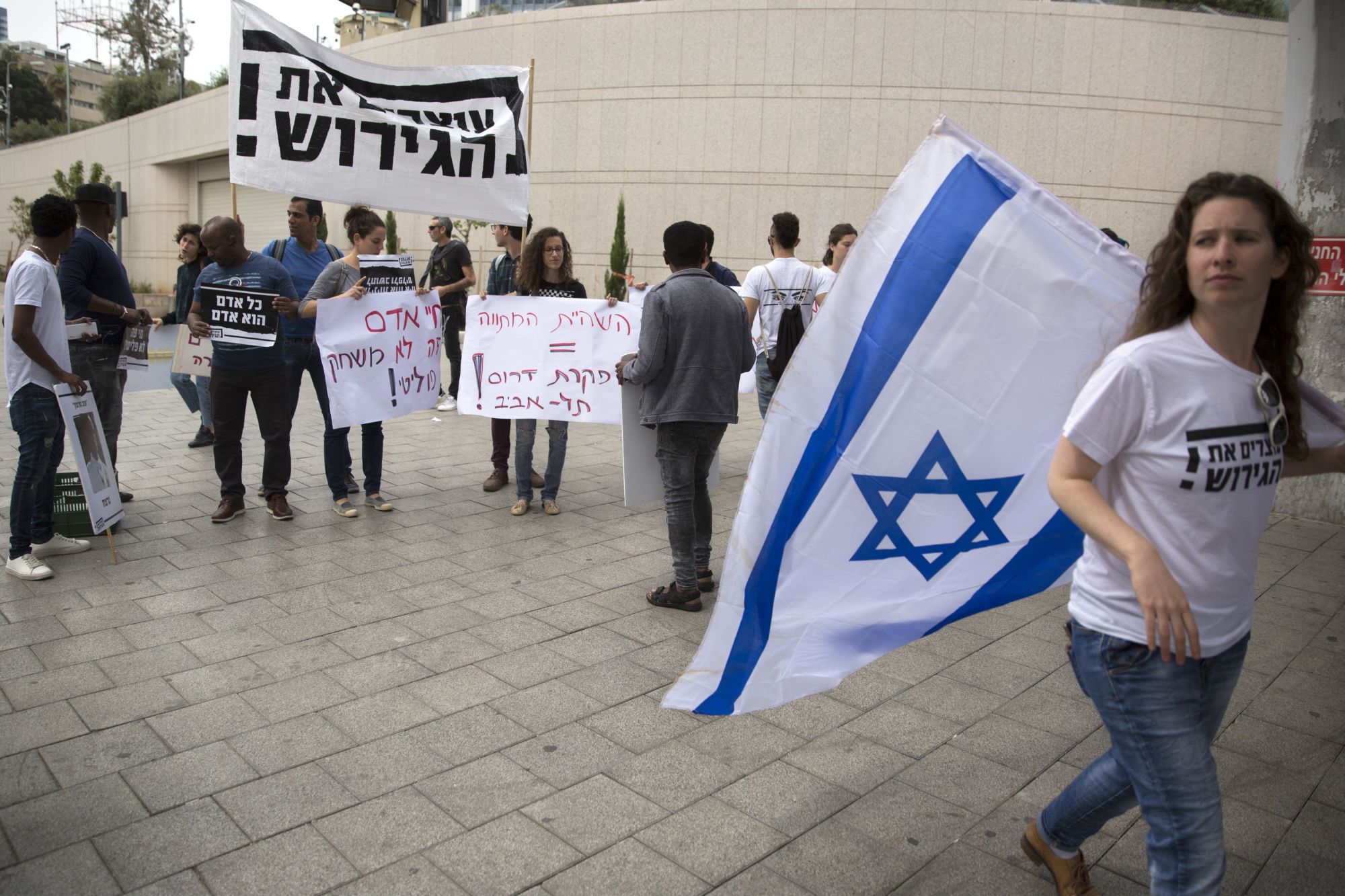 Hagyják abba a deportálást jelentésű héber felirattal tüntetnek afrikai migránsok kitoloncolása ellen Tel-Avivban 2018. április 3-án. Az előző napon Benjámin Netanjahu izraeli miniszterelnök bejelentette, hogy Izrael eláll az afrikai illegális bevándorlók kitoloncolásától, majd azt is, hogy felfüggeszti az ENSZ Menekültügyi Főbiztosságával (UNHCR) ugyanaznap megkötött megállapodásának végrehajtását. (MTI/AP/Sebastian Scheiner)