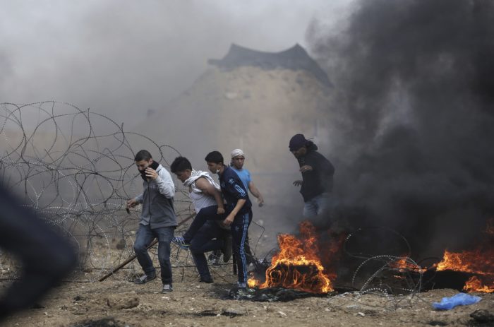 Izraeli-palesztin határ, 2018. április 27. Palesztin tüntetõk az izraeli katonák által helyezett szögesdrótkerítés közelében sûrû fekete füsttel égõ autógumik mellett az izraeli-gázai határon 2018. április 27-én. A Gázai övezetet uraló Hamász radikális iszlamista szervezet április eleji felhívására a palesztinok hat héten át tiltakoznak az izraeli blokád ellen, azt követelve, hogy visszatérhessenek földjeikre és otthonaikba, ahonnan a zsidó állam 1948-ban történt megalapításakor elûzték õket. (MTI/AP/Halil Hamra)