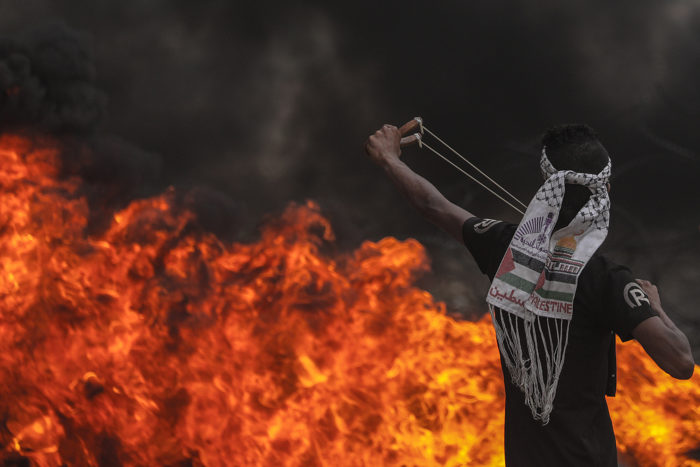Gázai övezet, 2018. május 4. Palesztin tüntető csúzlival lő izraeli katonákra a Gázai övezet déli részén 2018. május 4-én. Az izraeli határ mellett a hatodik egymás utáni pénteken tartott tüntetésen százhetven palesztin megsebesült, az egyikük súlyosan. (MTI/EPA/Mohammed Szaber)