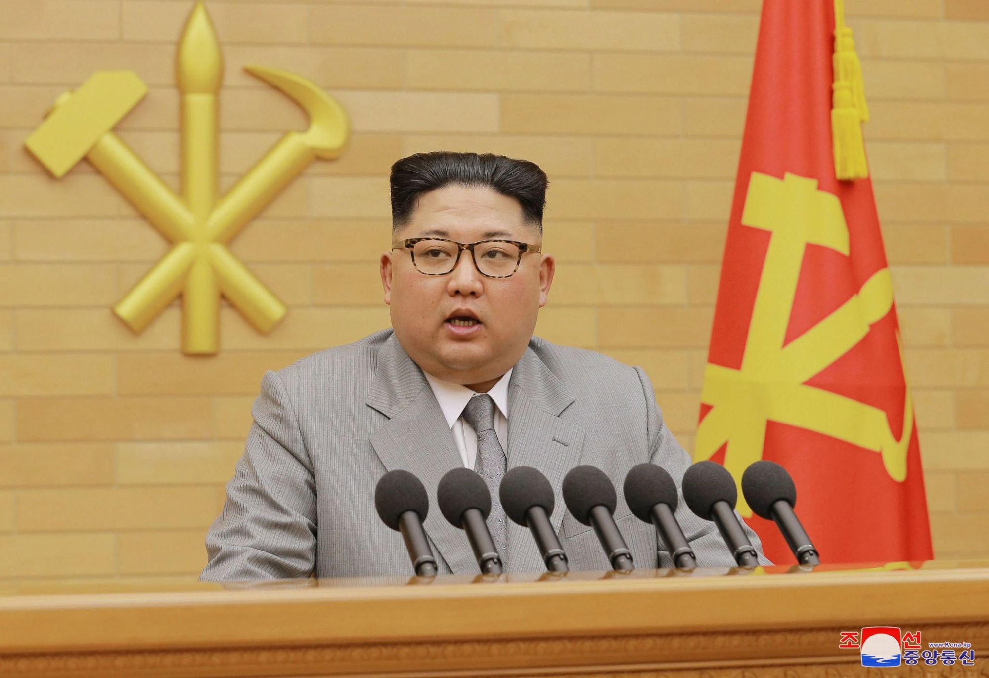 Az észak-koreai kormányzat által közreadott képen Kim Dzsong Un elsőszámú észak-koreai vezető, a kommunista Koreai Munkapárt első titkára újévi beszédét mondja 2018. január 1-jén, meg nem nevezett helyszínen. A vízjel koreai felirata a KCNA észak-koreai hírügynökség nevét jelenti. (MTI/AP/KCNA/Korea News Service)