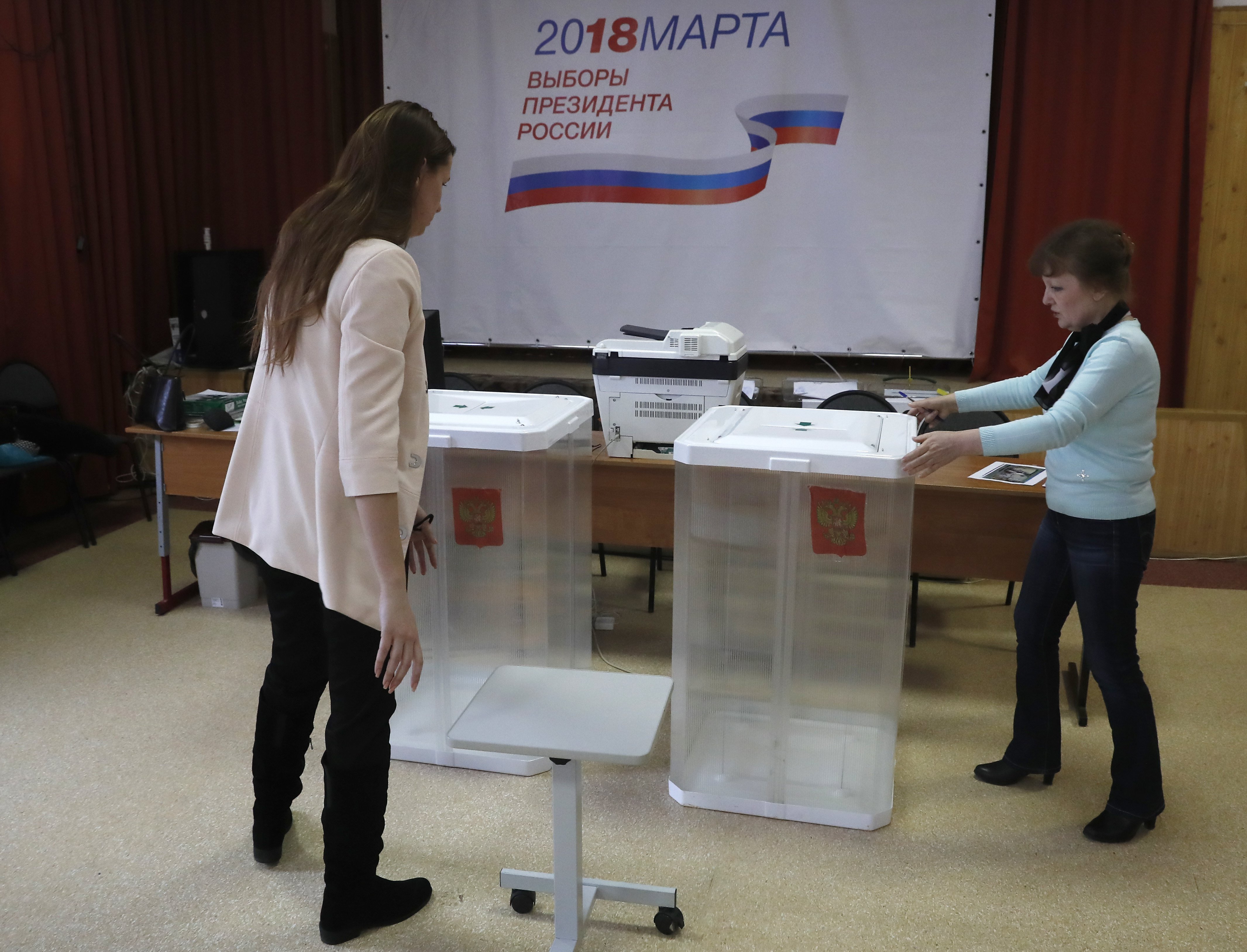 Moszkva, 2018. március 16. A helyi választási bizottság munkatársai urnákat állítanak fel egy moszkvai szavazóhelyiségben 2018. március 16-án, két nappal az orosz elnökválasztás előtt. A plakát feliratának jelentése: 2018. március - Oroszország elnökének megválasztása - A mi államunk, a mi elnökünk, a mi választásunk. (MTI/EPA/Szergej Ilnyickij)