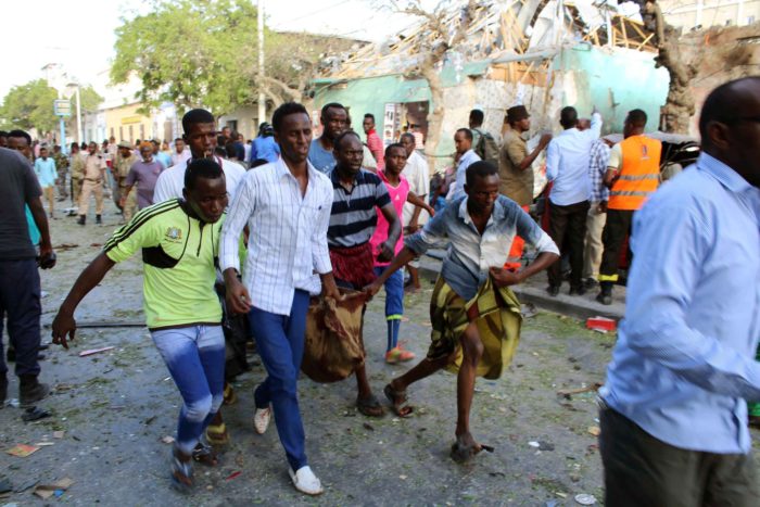 Sebesültet visznek szomáliai férfiak a fõváros, Mogadishu egyik belvárosi szállodája közelében, ahol autóba rejtett pokolgép robbant 2018. március 22-én. (MTI/EPA/Szaid Juszuf Varszame)